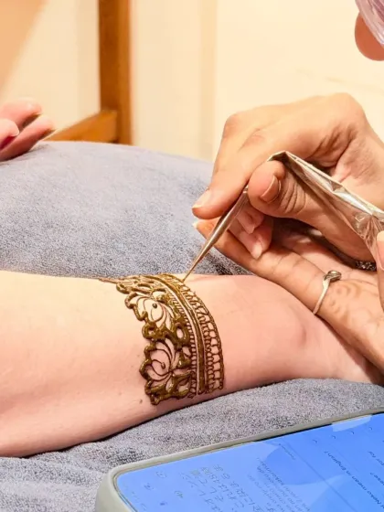 A close-up of the process, carefully creating a lotus cuff design with a fine-tipped cone.