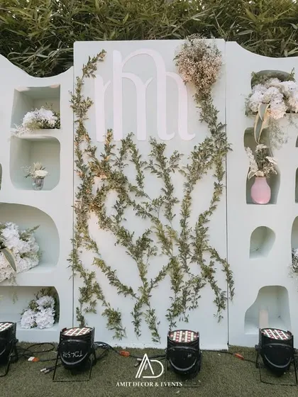 A unique and modern photo backdrop I designed. The wall features organic-shaped niches filled with white floral arrangements and a subtle monogram of the couple's initials.