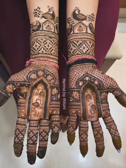This design is all about symmetry and grace. It features matching peacocks and swans on both hands, framed by architectural jharokhas and fine jaal work.
