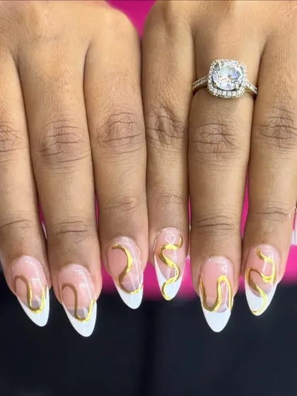 Elegance with a creative flair. These almond-shaped extensions feature a classic white French tip, elevated with abstract golden swirls for a unique and luxurious touch.