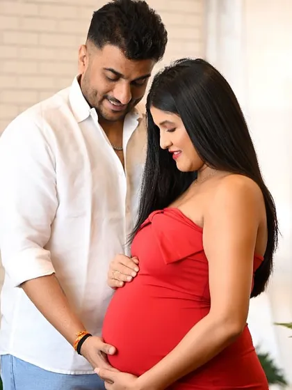 A classic maternity pose with the couple looking down at the baby bump, filled with love and wonder.