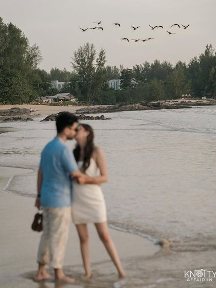 A creative use of focus, with the flock of birds sharp against the soft-focus kiss of the couple. This artistic choice adds a layer of storytelling and visual interest to their beach portrait.