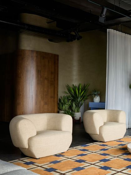 A pair of sculptural, cream-colored armchairs against a backdrop of dark wood paneling. This vignette highlights how I use contrasting forms and colors to make individual pieces stand out.