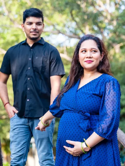 A stylish portrait of the couple in a park. The focus is on the mom-to-be, who is leading her partner forward on their journey.