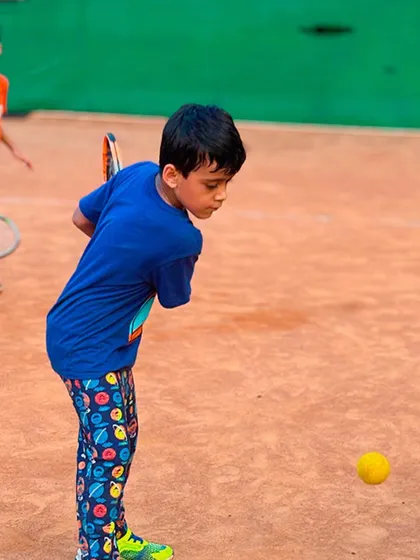 A young player mid-swing, focusing on his backhand. You can see his concentration as he prepares to connect with the ball.