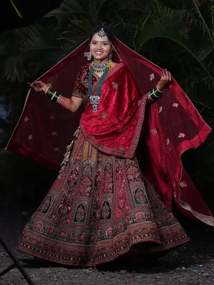 A full view of this gorgeous bride, her red velvet dupatta spread out to showcase the beautiful embroidery of her wedding lehenga.