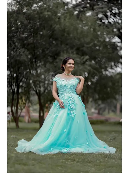 This full-length shot in a park setting highlights the dreamy quality of the light blue ball gown. The off-shoulder neckline and floral details create a timelessly romantic look.