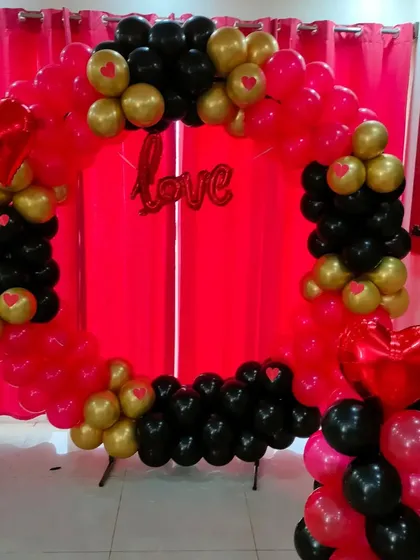 A romantic decoration with a square-shaped balloon frame in red, black, and gold, with a 'Love' foil balloon in the center.