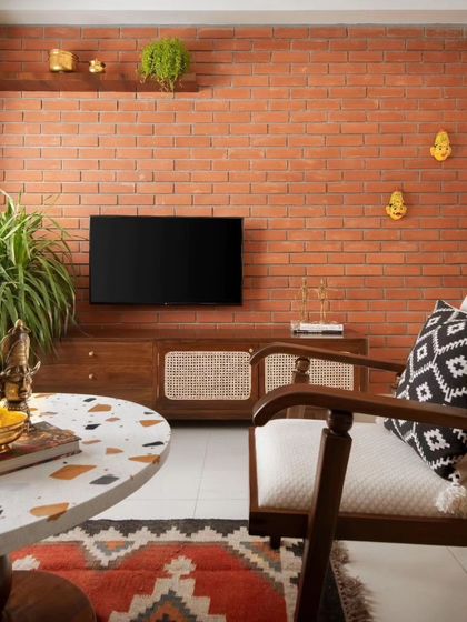 The living room's focal point is the exposed brick wall, which adds texture and warmth. The custom TV console with cane paneling continues the material theme, creating a cohesive look.