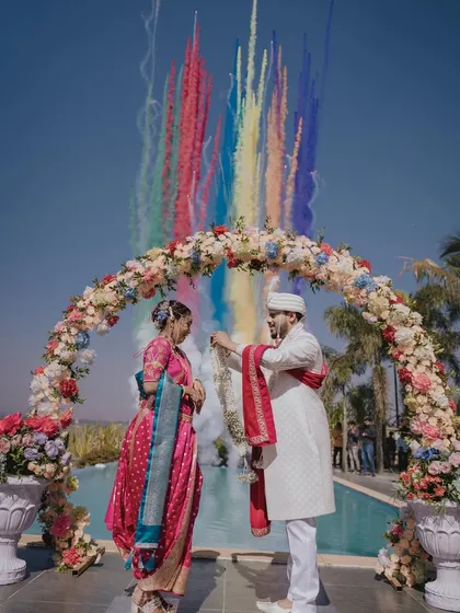 A spectacular varmala moment with rainbow-colored smoke. The bride's vibrant saree and joyful expression make this a truly unforgettable wedding photo.