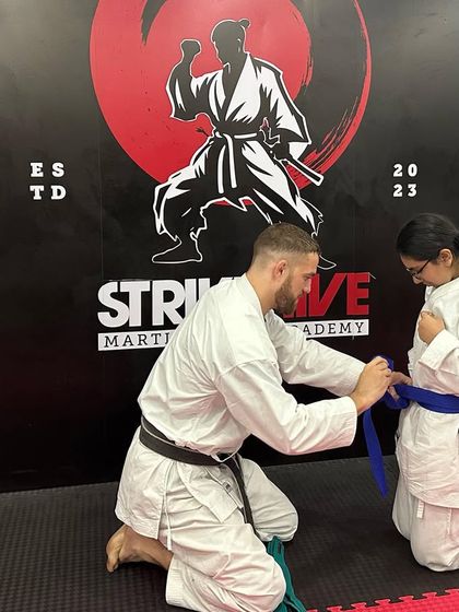 A student receives her new blue belt, a symbol of her progress and commitment. We take pride in watching our students advance through the ranks.