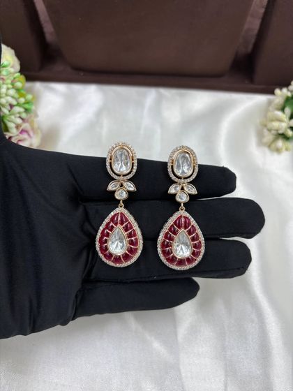 A beautiful Moissanite and AD necklace set with green or red Meenakari detailing. The combination of oval and teardrop stones gives this piece a unique and luxurious appeal.