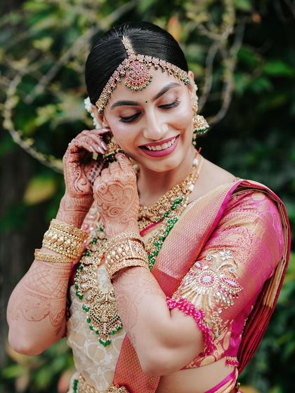 A close-up portrait of a bride, capturing her serene smile and the detailed craftsmanship of her wedding jewelry.
