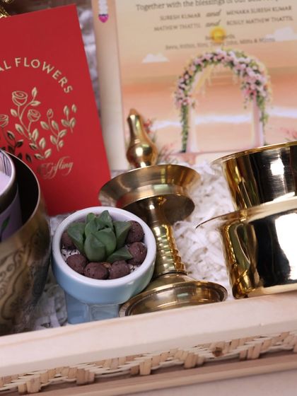 A detail shot showing the small succulent plant and traditional brass lamp, part of the elegant wedding invitation hamper.