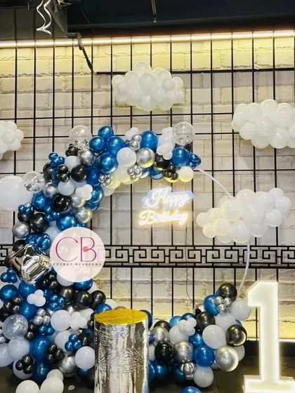 A full shot of our popular cloud-themed birthday decor. This setup is perfect for first birthdays, featuring a crescent-shaped balloon arch, a light-up number '1', and a neon 'Happy Birthday' sign for that perfect photo opportunity.