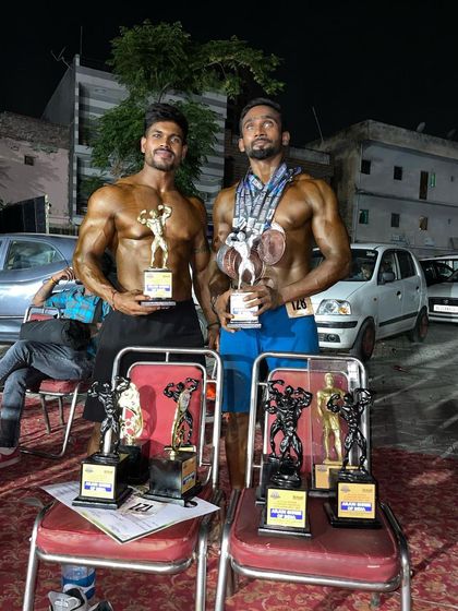Two of my top athletes showing off their hard-earned trophies. You can see the muscle definition and conditioning that set them apart from the competition.