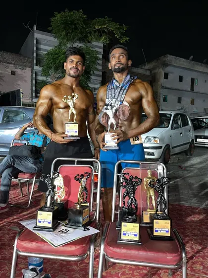 Two of my top athletes showcasing their trophies. Their conditioning and muscle definition are a direct result of a strict, personalized training and nutrition protocol.