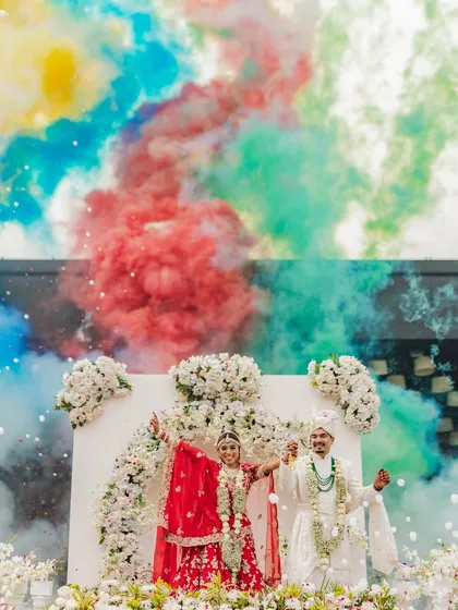 A burst of color for a burst of love. This shot of Rahul and Riya during their Varmala uses colored smoke to create a vibrant, high-energy photograph that perfectly matches the joy of the moment.