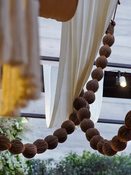 A unique detail of a garland made from dried coconut shells, adding a rustic and unexpected texture to the fabric-draped ceiling.