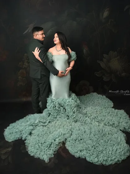 A classic dance-style pose for an expecting couple. This elegant portrait in a stunning pastel green gown captures a moment of romance and connection.