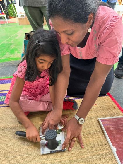 Guided by her mother, a young girl learns the technique of flower pounding. This collaborative process strengthens their bond and builds the child's confidence in her artistic abilities.