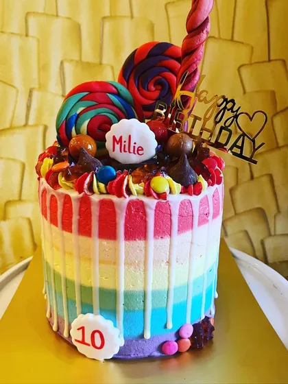 Let your imagination run wild with my custom themed cakes. This Candyland cake, made for a 10th birthday, is a vibrant example of my craft, featuring a rainbow-striped vanilla cake with blueberry compote, topped with a delightful collection of lollipops and candies.