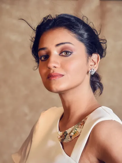 A close-up portrait of Hruta Durgule from a special photoshoot. The focus here was on a sophisticated and modern aesthetic, highlighted by the unique neckline of the white gown.