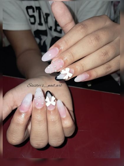 A still image of this creative French manicure, showing the contrast between the soft ombre, the sharp black tip, and the delicate 3D bow.