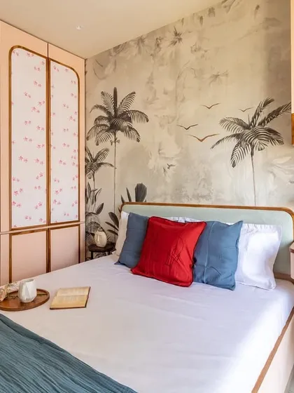 A closer look at the handle-less wardrobe with delicate floral-patterned shutters, which complements the stunning botanical mural on the bed's backdrop.