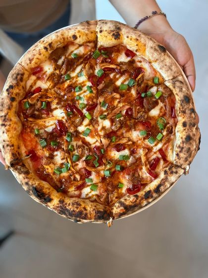 A full view of the Adobo Chicken pizza, held up and ready to be served. It's a beauty.