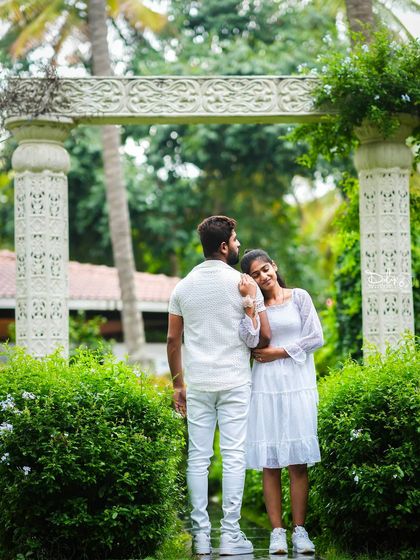 A romantic pose in front of a white stone archway in the garden.