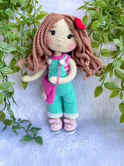 This is the same doll in her second outfit! This set includes mint green overalls, a pink floral bag, and a cute red hair clip. Having multiple outfits makes playtime even more exciting.