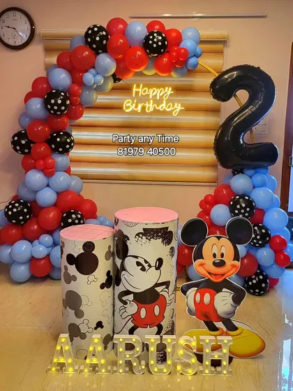 This Mickey Mouse setup for Aarush's 2nd birthday features a classic color scheme, a large number '2' foil balloon, and a character cutout for photos.