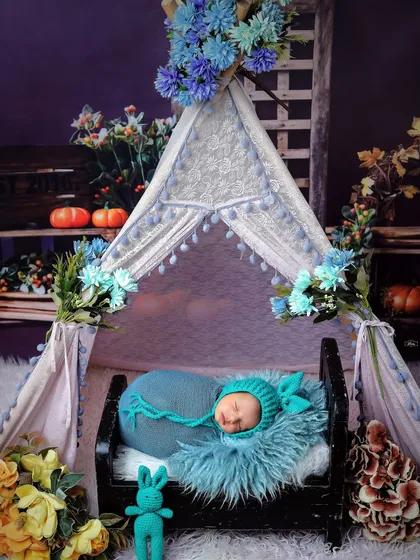 This cozy camp-themed setup features a newborn sleeping in a tiny bed inside a decorated tent. We have a variety of creative themes to make your baby's photoshoot special.