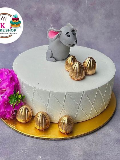 A unique cake for Ganesh Chaturthi featuring Mooshak, Lord Ganesha's loyal mouse companion. The cake is decorated with golden modak-shaped chocolates.