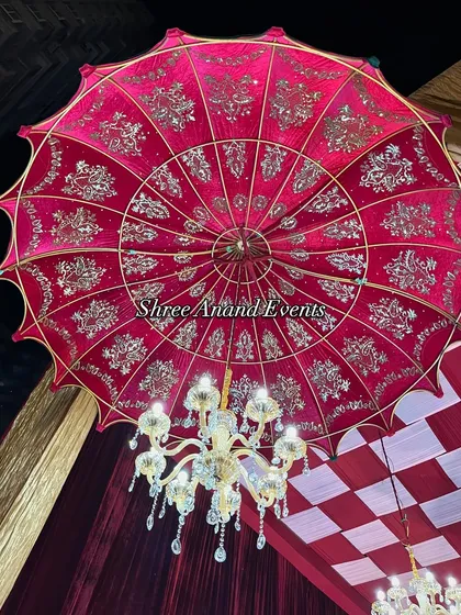 A close-up of a stunning red velvet umbrella with intricate gold embroidery, used as a magnificent ceiling centerpiece.