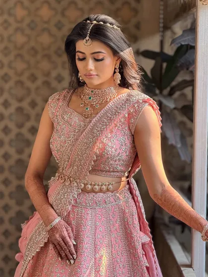 A beautiful three-quarter portrait of the bride, showcasing her full look and the intricate details of her lehenga.
