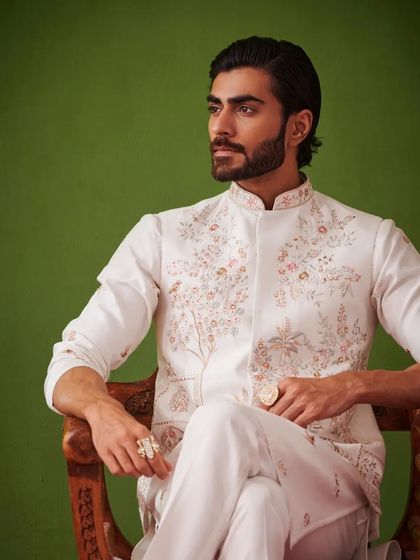 A seated pose in the white kurta set, exuding an aura of calm and confidence. The Nazaakat collection is designed for the modern man who appreciates fine craftsmanship.
