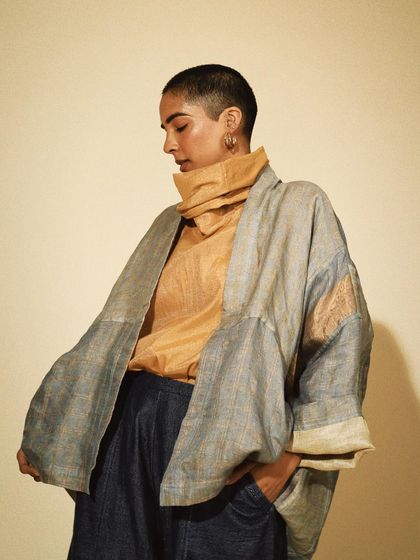 A chic, layered look featuring a silk turtleneck and an open jacket. This studio shot highlights the elegant drape and texture of the sustainable fabrics.