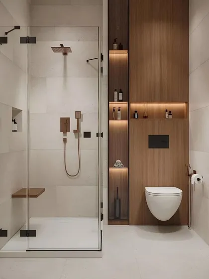 This bathroom design proves that even compact spaces can feel luxurious. We used a combination of warm wood panelling with integrated shelving niches and a frameless glass shower enclosure to create a space that is both highly functional and visually serene.