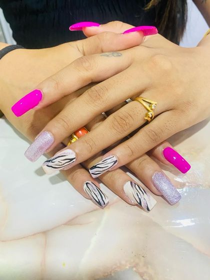 A full view of the zebra print nail set. The combination of bold pink, glitter, and animal print creates a fun and fashionable look, expertly executed by a student.