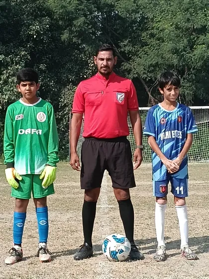 The two captains and the referee at the center circle before the start of a U-13 league game.