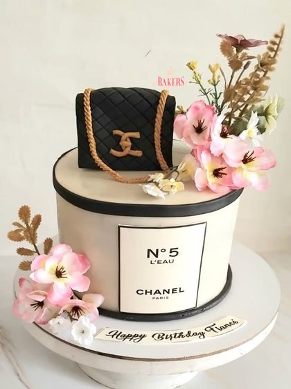 A super pretty Chanel-themed floral cake for a fiancé's birthday. This elegant design combines the iconic Chanel No. 5 branding with a classic quilted bag and beautiful pink flowers.