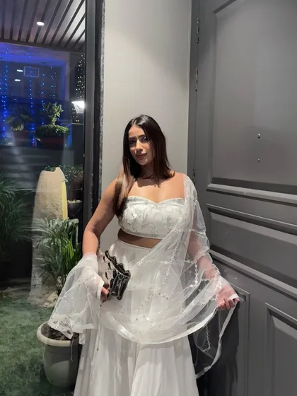 A full-length view of the elegant white lehenga, showing its graceful silhouette against an evening backdrop.