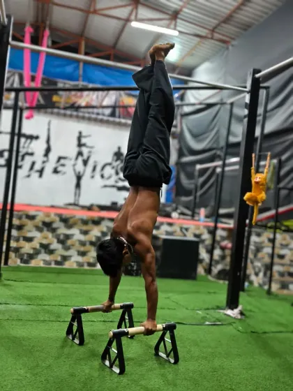 A clean handstand on parallettes, demonstrating core stability and shoulder strength. We build up to this with dedicated practice.