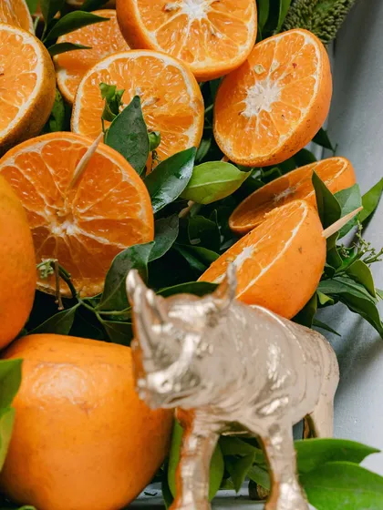 A close-up of the decor details, showing a golden rhino figure nestled amongst fresh tangerines and green leaves.