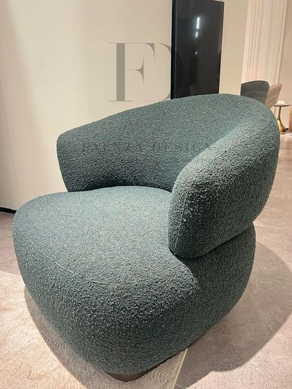 A modern armchair in a green bouclé fabric. The chair's unique, organic shape and textured upholstery make it a standout piece that adds both comfort and sculptural interest.