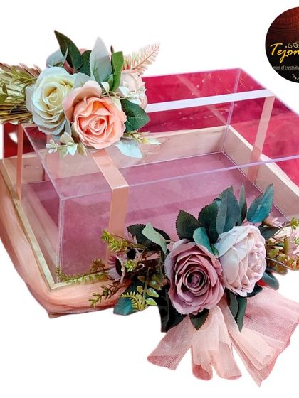 An empty premium acrylic gift box, ready to be filled with love and thoughtful presents. The floral arrangement on top adds a touch of elegance.