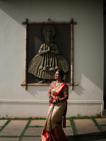 A moment of quiet elegance. The bride stands gracefully, her traditional attire and flawless makeup making for a stunning photograph against a cultural backdrop.
