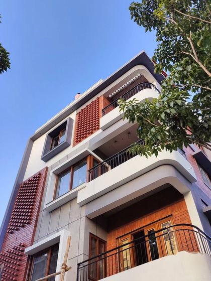 A different angle of the Akshaynagar facade under construction, highlighting the interplay of curved balconies and textured brick panels.